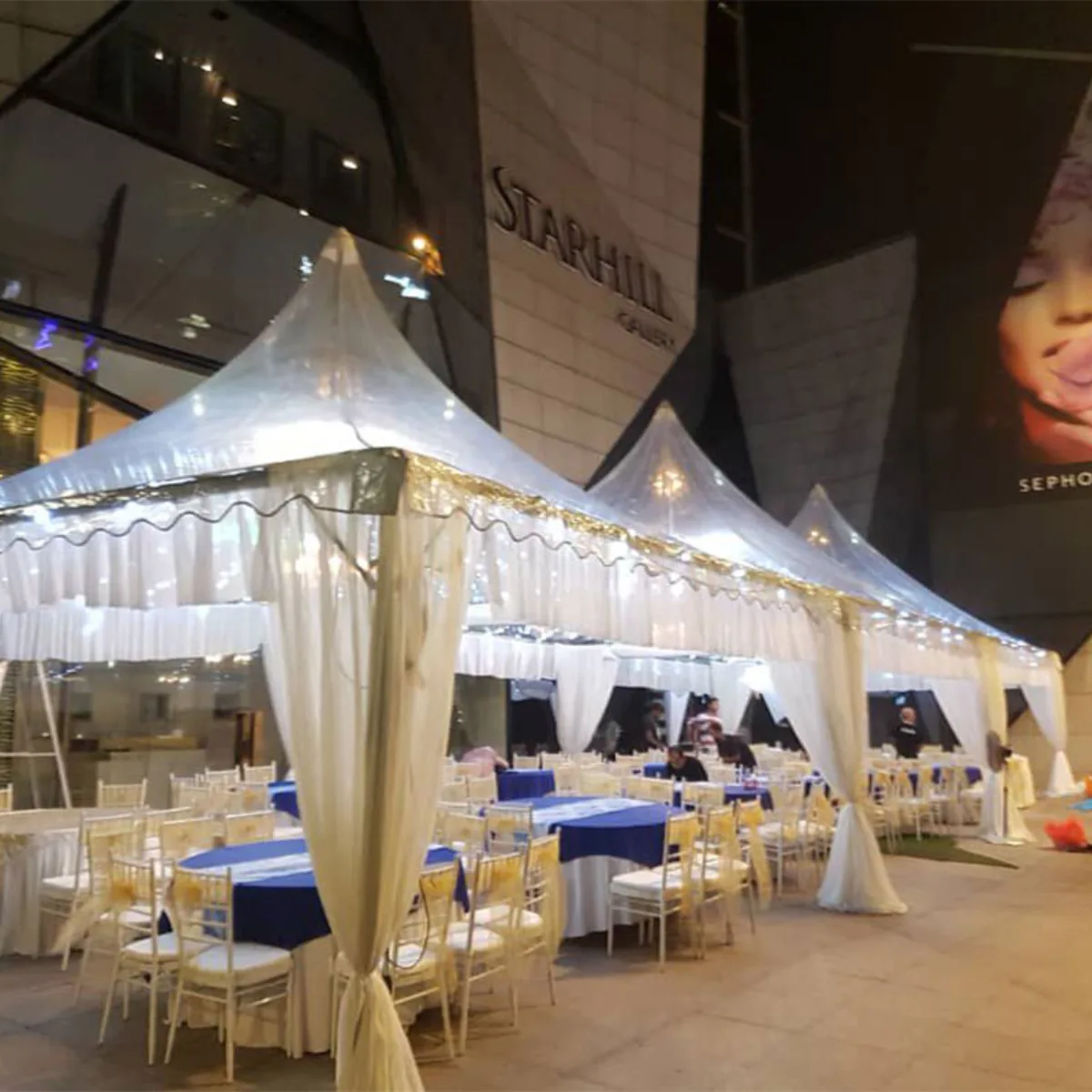 Lit hospitality tents installed beside a venue at night
