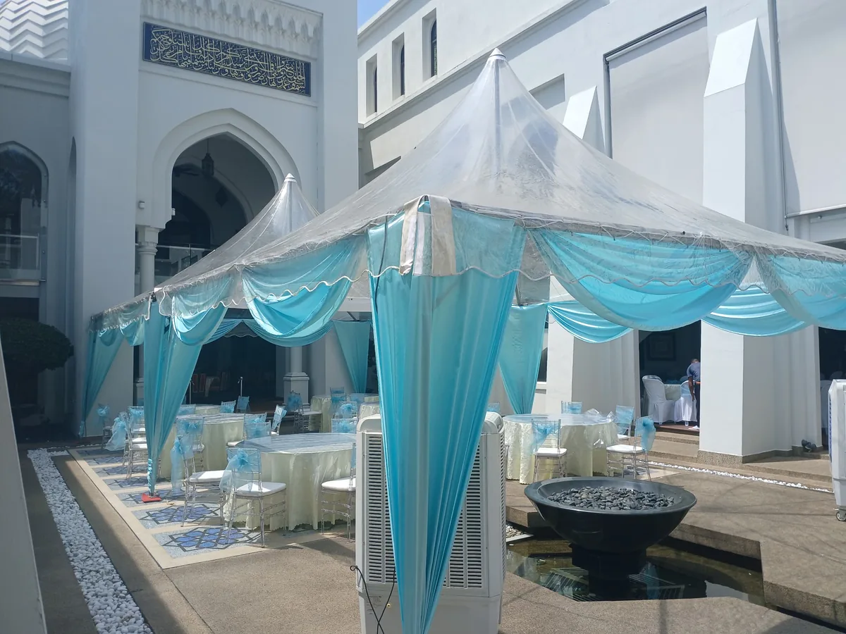 Clear-top canopy with blue draping over round tables in a courtyard
