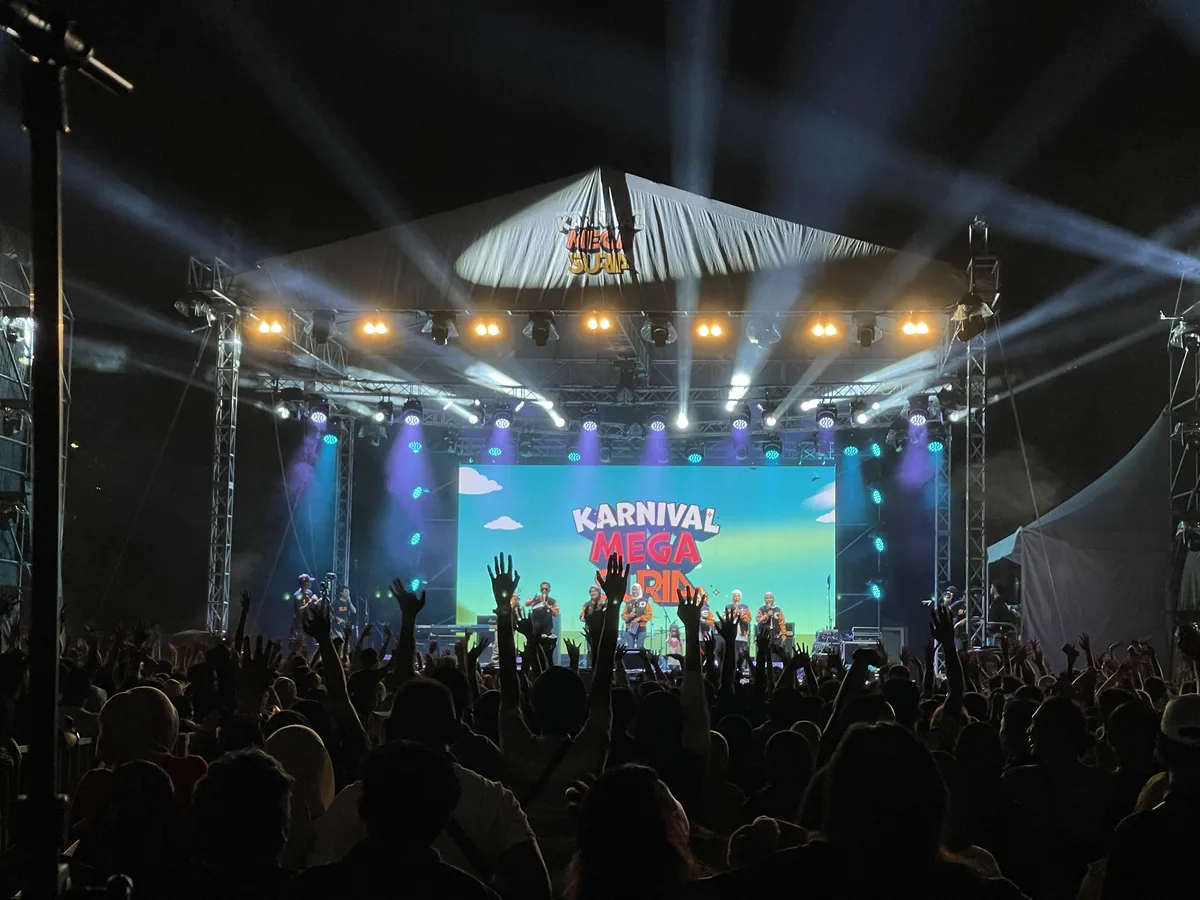 Audience with raised hands in front of a concert stage and LED screen