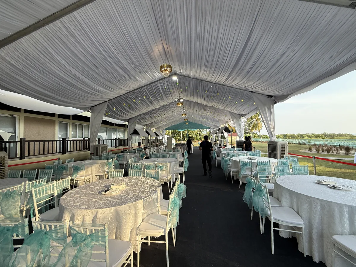 Marquee dining area with round tables, open to a sea view