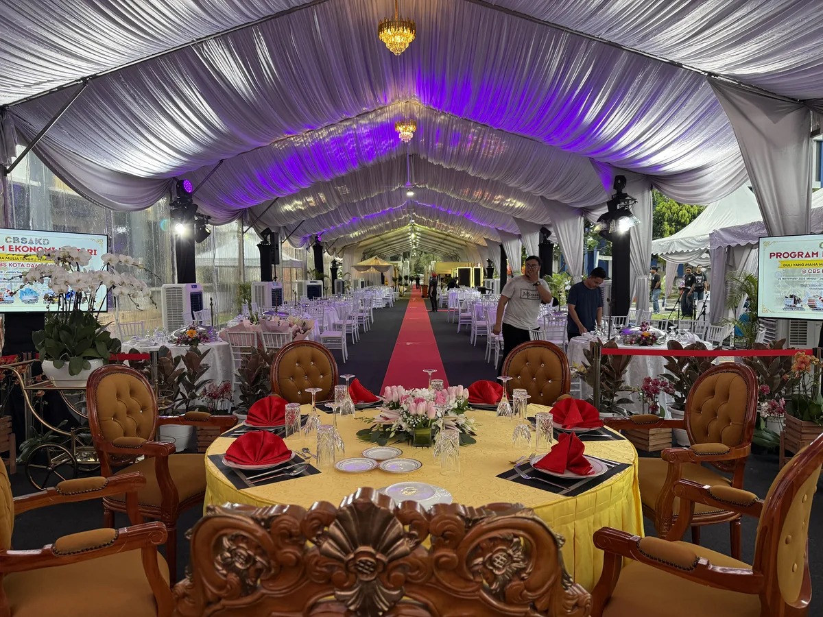 Head table with carved chairs under purple-lit marquee draping