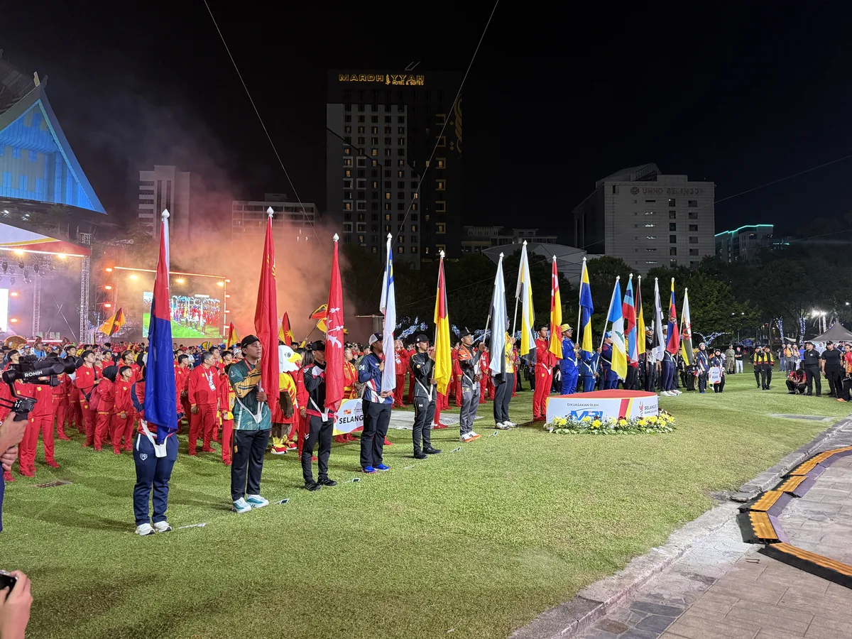 Flag bearers lined up on a lawn with stage lights and smoke behind