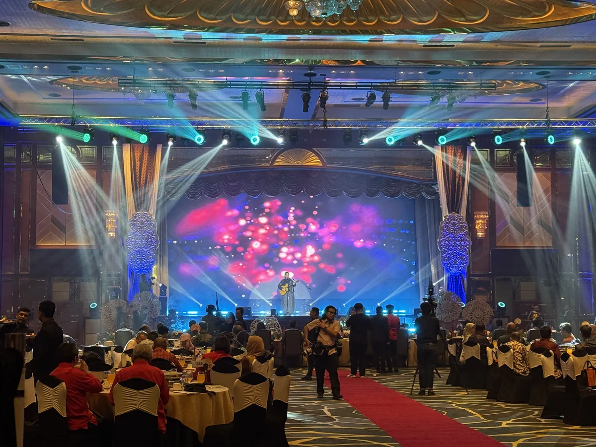 Performer on a gala stage with pink LED visuals and moving-head beams